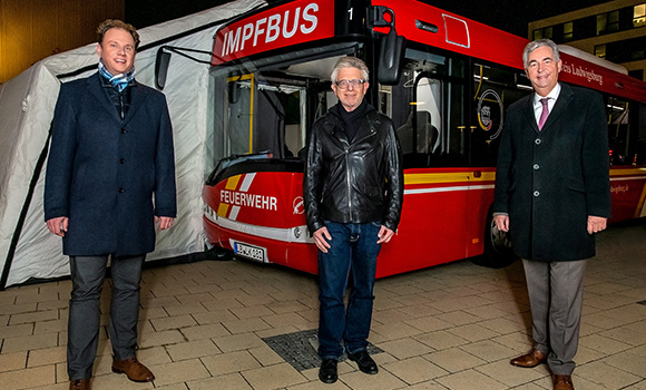 Oberbürgermeister Matthias Knecht, Klinikenchef Jörg Martin und Landrat Dietmar Allgaier  stehen vor einem roten Bus mit der Aufschrift "Impfbus".