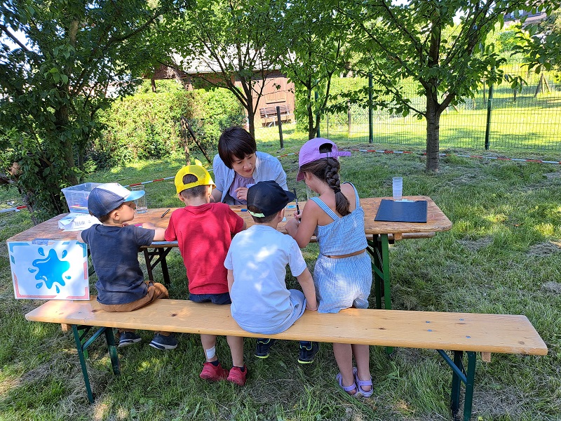 Drei Kinder am Maltisch mit Betreuung