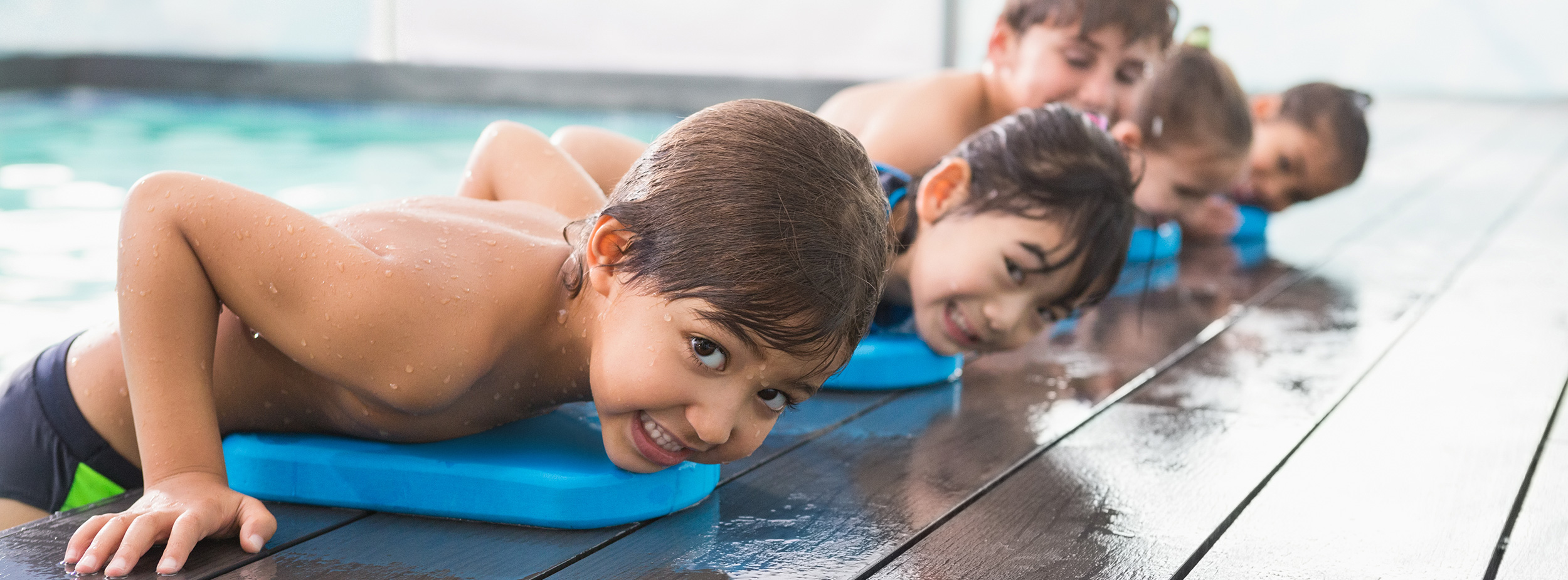 Kinder auf Schwimmbrettern beim Schwimmkurs