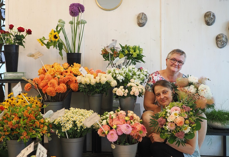 Zwei Frauen sitzen mit Blumenstrauß im Blumenladen