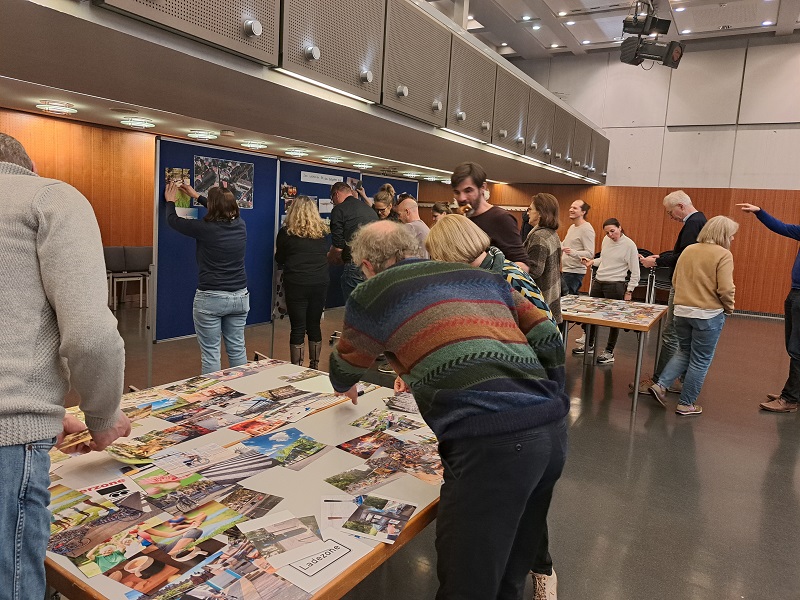 Personen vor Tischen und Pinnwänden beim Workshop