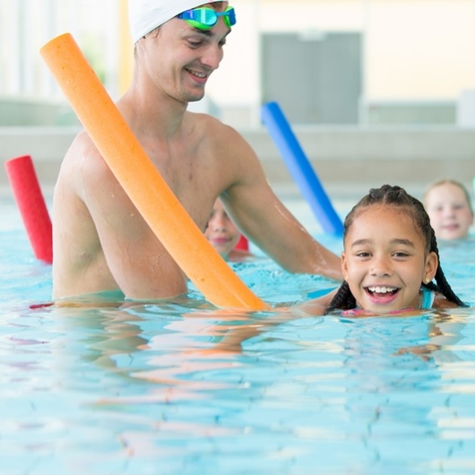 Schwimmlehrer mit Kind beim Schwimmunterricht