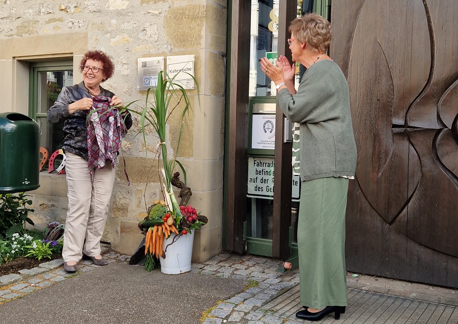 Frau Kretschmann hat ein Schild an der Wand enthüllt, eine Frau applaudiert