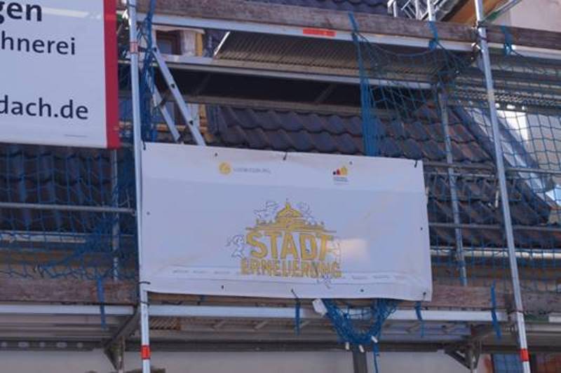 Das Banner der Stadterneuerung wird am Gerüst der Baumaßnahme angebracht.