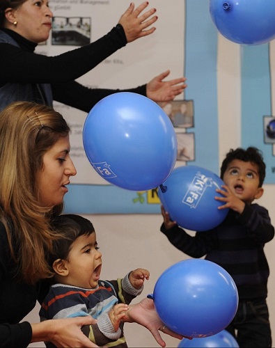 KiFa-Spielgruppe Kinder die mit blauen Luftballons spielen